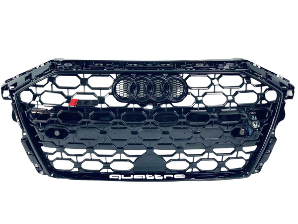 A black honeycomb car grille displays the Audi rings logo at the center and "quattro" text at the bottom. It features a small "RS" badge on the left.
