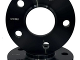 A black metal wheel spacer with multiple holes sits on a matching base, displaying the text 