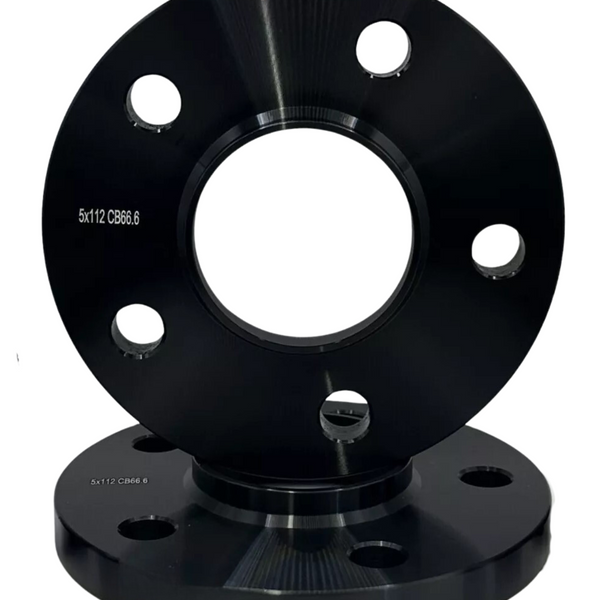A black metal wheel spacer with multiple holes sits on a matching base, displaying the text "5x112 CB66.6."