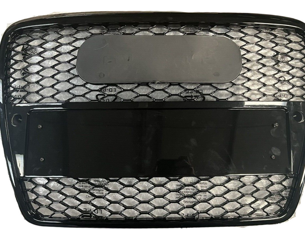 A black, rectangular grille with hexagonal mesh inserts is positioned on a white background. The grille features two rectangular sections, one obscured by a dark, reflective panel.