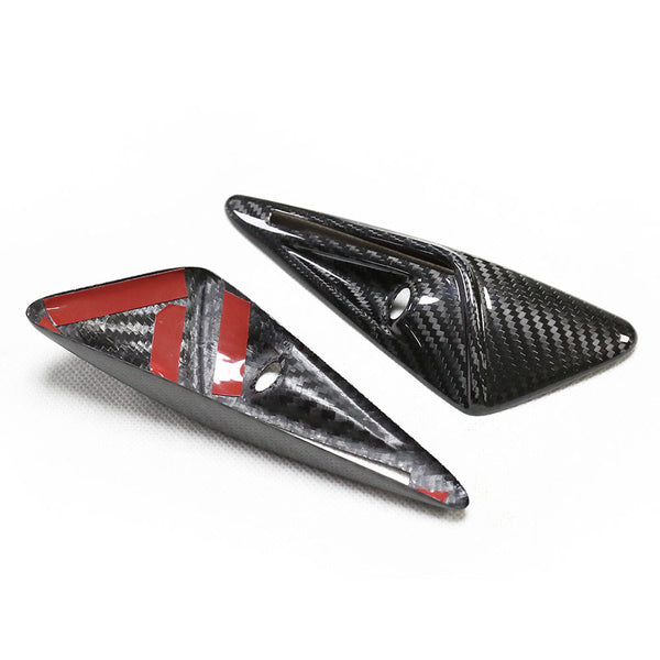 Two triangular carbon fiber pieces are positioned on a white surface. One piece has red adhesive strips and a circular hole, indicating they may be mounting components.