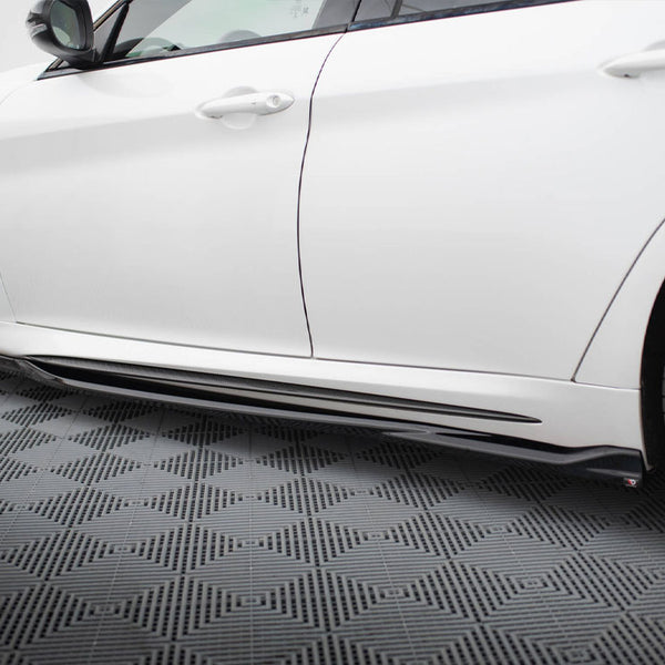 A white car is parked, showcasing its sleek side and black side skirt, on a patterned grey floor with geometric designs.