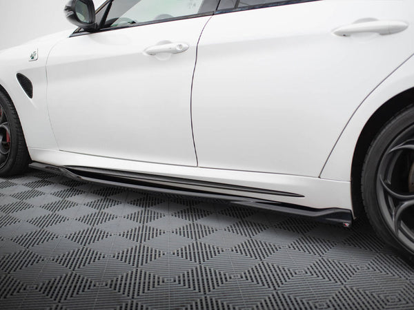 A white car is parked, showcasing its sleek side and black side skirt, on a patterned grey floor with geometric designs.