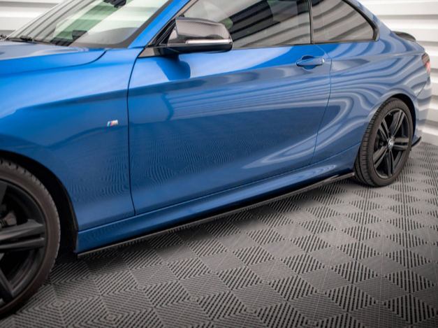 A blue sports car with sleek, aerodynamic lines is parked on a textured gray floor inside a modern, well-lit garage.