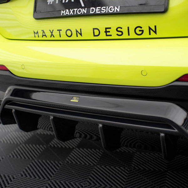 Bright yellow car features a black rear diffuser. "#MAXTON DESIGN" text is on the vehicle and license plate, parked on a patterned black floor.