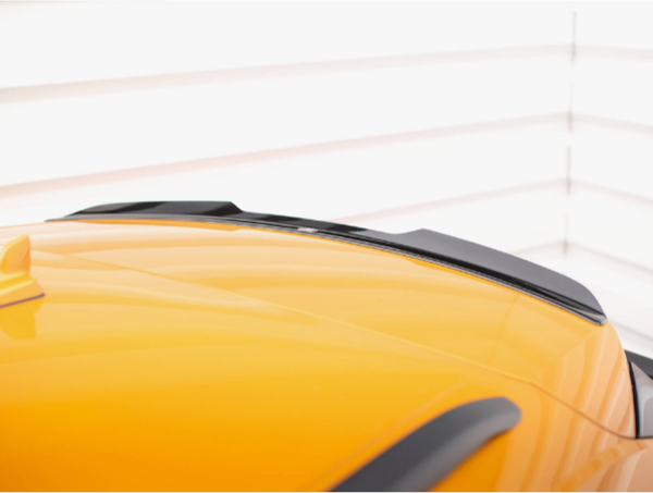 A yellow car roof with black roof rails is shown; it is parked with a white, horizontal-striped wall in the background.