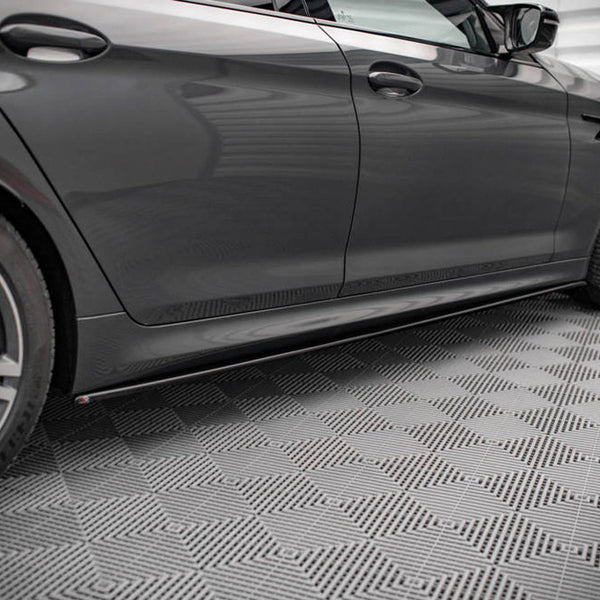 A sleek, grey car parked on a textured, patterned floor inside a well-lit garage, highlighting its elegant design features and alloy wheels.