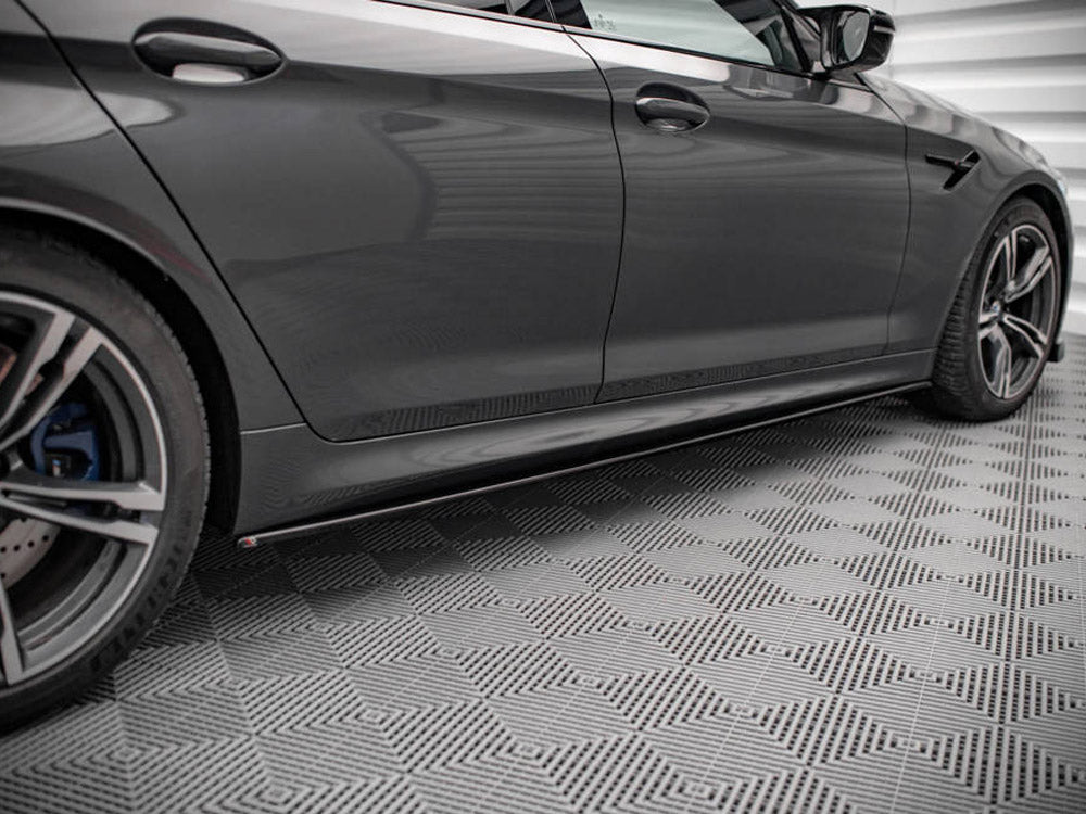 A sleek, grey car parked on a textured, patterned floor inside a well-lit garage, highlighting its elegant design features and alloy wheels.