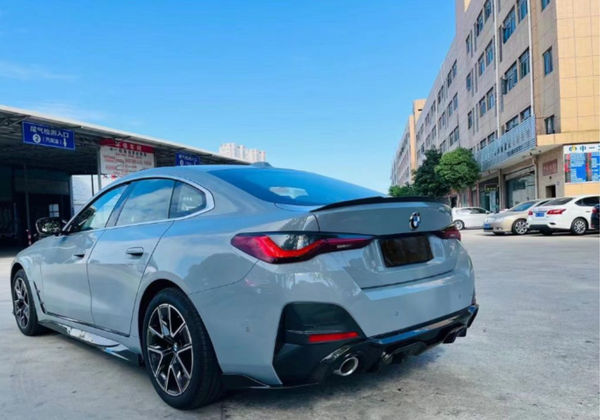 A gray car is parked near a commercial building under a clear sky. Nearby, other vehicles and signs with Chinese text are visible, indicating a bustling urban environment.