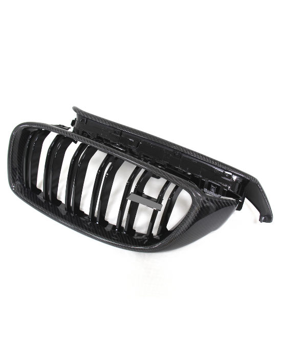 A black, shiny car grille with vertical slats and a carbon fiber texture, rests on a white background, suggesting its use as a vehicle front-end component.