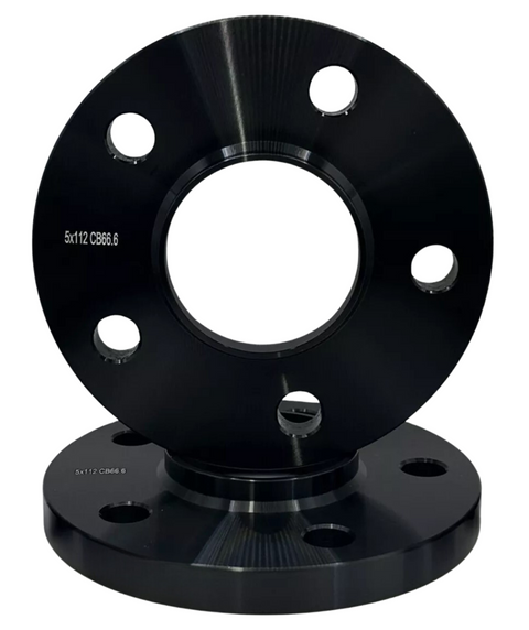 A black metal wheel spacer with circular holes is stacked upright on another. Both have the text "5x112 CB66.6" engraved on them, against a plain white background.
