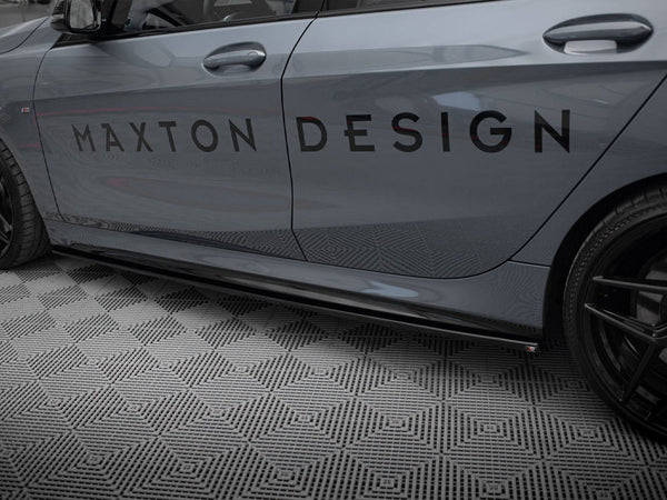 Car side displaying the text "MAXTON DESIGN" on its door, parked on a diamond-patterned floor. The vehicle is grey with black wheels, shown in a garage setting.