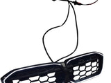 A black, hexagonal-patterned car grille with LED lights is connected to two wires. It is set against a plain white background.