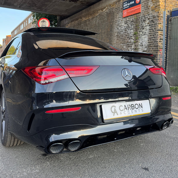 Car with a sleek black exterior parked under a bridge, displaying a "Carbon Accents" license plate. Red taillights glow, while a sign above warns of restricted vehicle height.