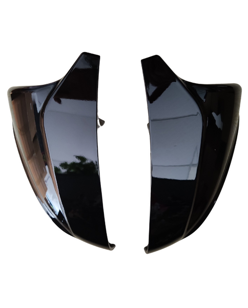 Two glossy black side mirrors are positioned facing each other against a white background, reflecting faint indoor patterns and light.
