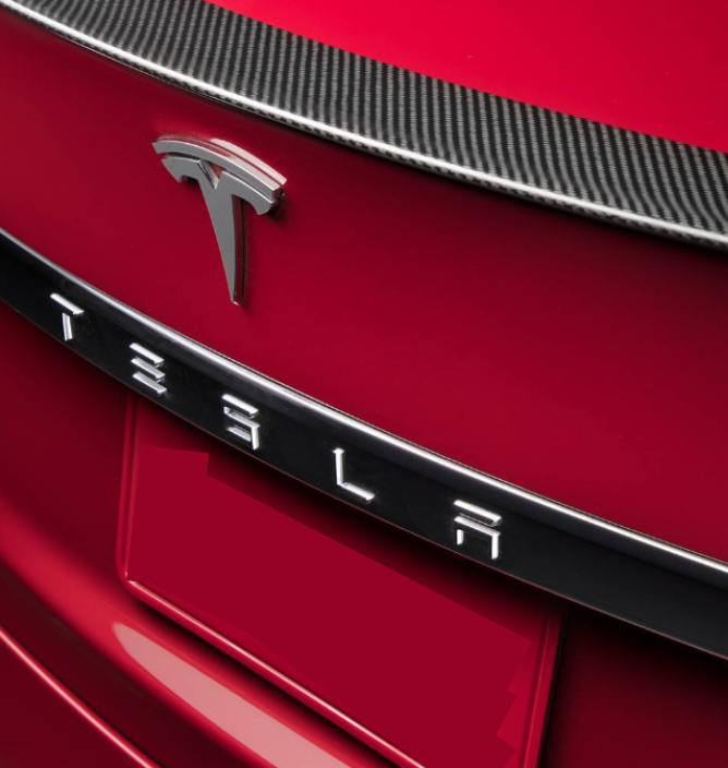 A red car features a prominent Tesla emblem and lettering on the rear, with a carbon-fiber trim above.
