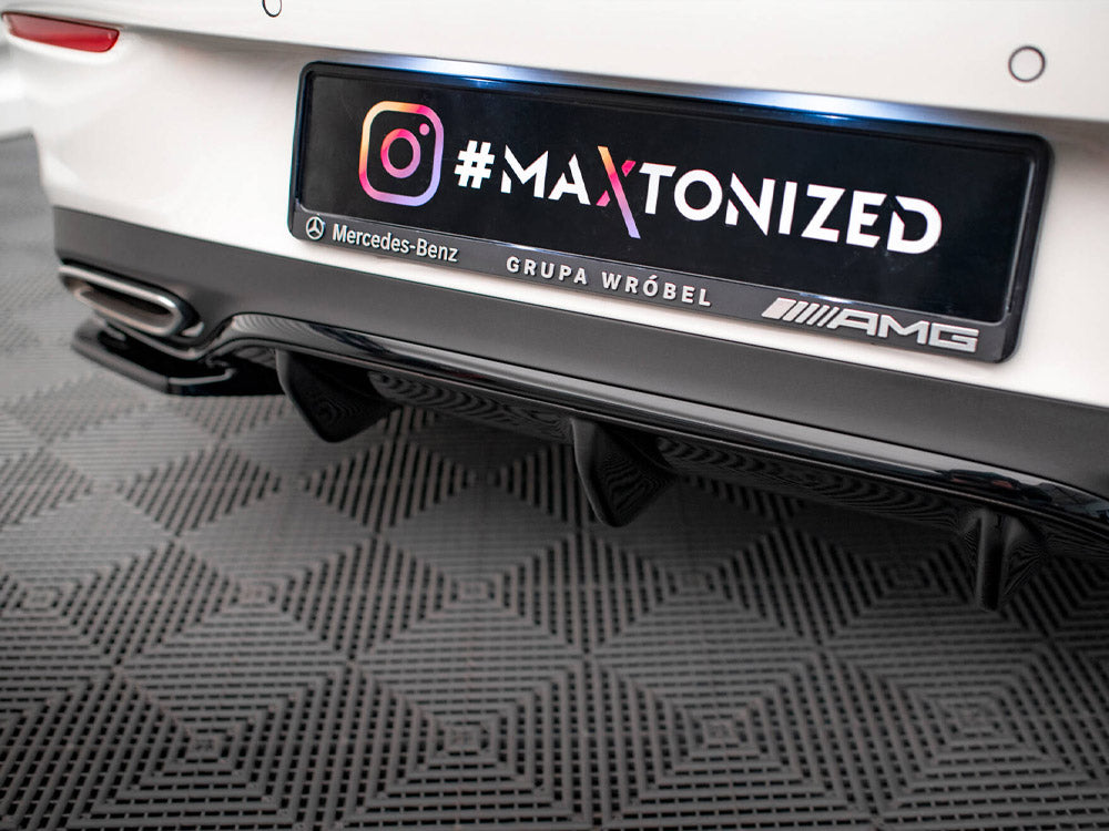 Car rear features a customized license plate with "#MA XTONIZED," Instagram logo, "Mercedes-Benz GRUPA WRÓBEL AMG," above a black bumper and exhausts, parked on a patterned floor.
