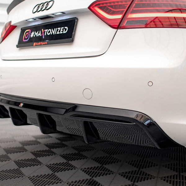 A white car's rear, featuring visible black diffuser and red taillights, is in a garage. The license plate reads "#MAXTONIZED." The floor has a checkered pattern.