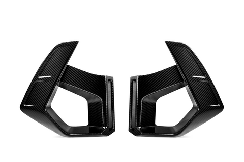 Two carbon fiber vent covers facing each other, featuring sleek, angular designs. They are positioned against a plain white background, highlighting their glossy texture and geometric shapes.