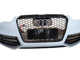 A car's front bumper features a black honeycomb grille with four interlocking rings and 