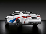 A white sports car with blue and red accents is parked in a dark studio setting. It features a rear spoiler, quad exhaust, and sleek lines highlighting its aerodynamic design.