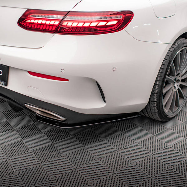 A white car with illuminated tail lights sits on a textured floor. The rear bumper features a dual exhaust, and a license plate displays "#MAXTONIZED."