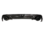 A glossy black car bumper with a honeycomb grille design, featuring circular exhaust openings on each side, isolated against a white background.