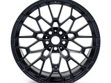 A black, intricately designed alloy wheel with a multi-spoke pattern, positioned upright on a plain white background, displaying an 