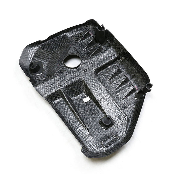 The object is a black, textured, rectangular panel with multiple protrusions, including a central hole, situated on a plain white background.