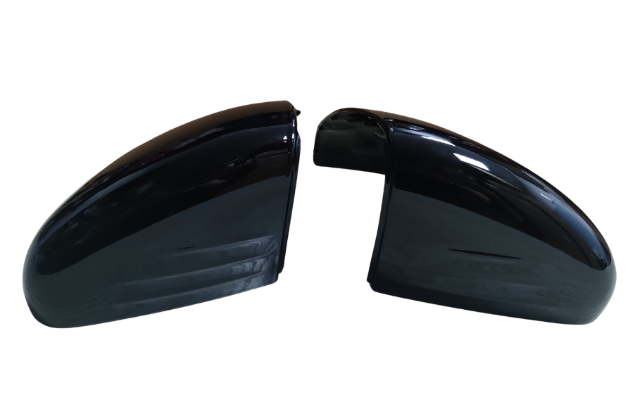 Two glossy black car side mirror covers face each other on a white background, showing smooth, curved surfaces and reflection patterns.