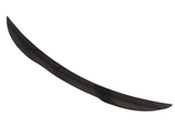 A curved, black, elongated car spoiler is positioned against a plain white background, showcasing its sleek aerodynamic design.