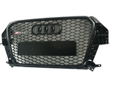 A black car grille with a honeycomb pattern, features four interlocking rings emblem and 