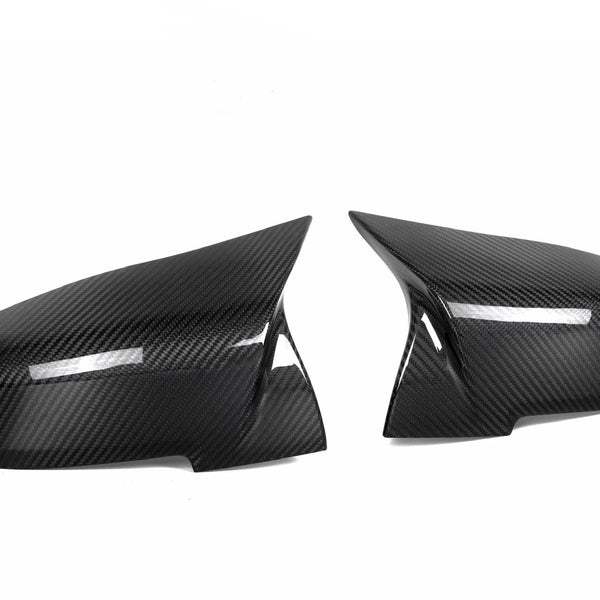 Two black carbon fiber car side mirror covers are positioned against a plain white background, showcasing their glossy, textured surface and sleek, aerodynamic shape.