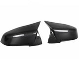 Two sleek carbon fiber side mirror covers are positioned facing each other against a plain white background. The glossy texture highlights their aerodynamic design.