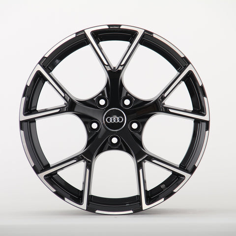 A sleek black alloy wheel with a glossy finish and five split spokes, featuring the Audi logo in the center, displayed against a plain white background.