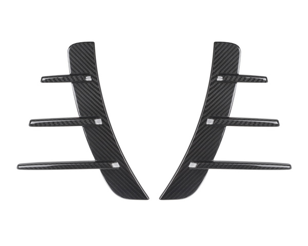 Two black carbon fiber pieces with three horizontal fins each are symmetrically aligned. They are set against a plain white background, suggesting automotive parts.