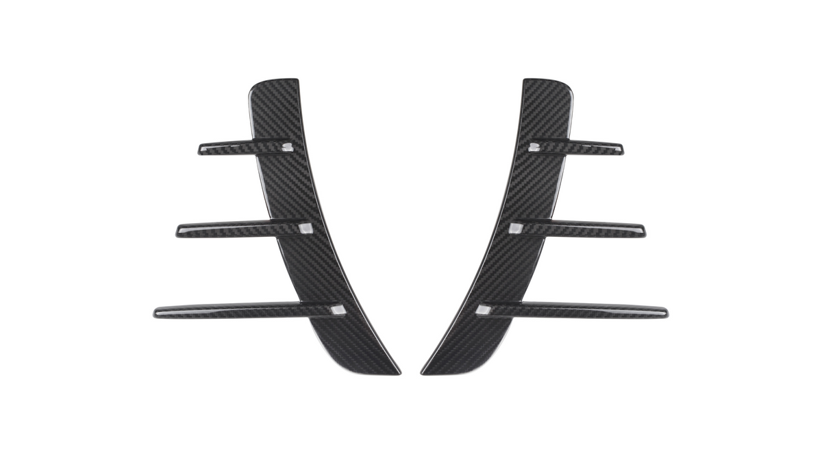 Two black carbon fiber pieces with three horizontal fins each are symmetrically aligned. They are set against a plain white background, suggesting automotive parts.