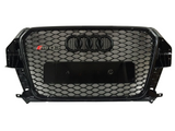 A black car grille features a honeycomb mesh design with the Audi four-ring emblem and 