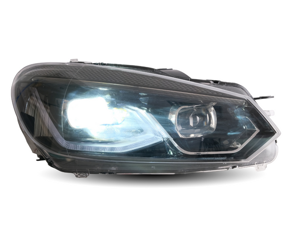 A car headlight shines brightly, encapsulated in a transparent casing, showcasing modern angular design elements. The background is plain white, emphasizing the headlight's features.