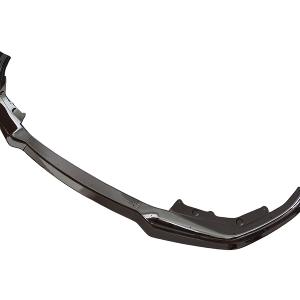 A shiny, curved car bumper sits isolated on a white background. Its sleek, metallic surface has slight curves and indentations typical of a vehicle's front end component.