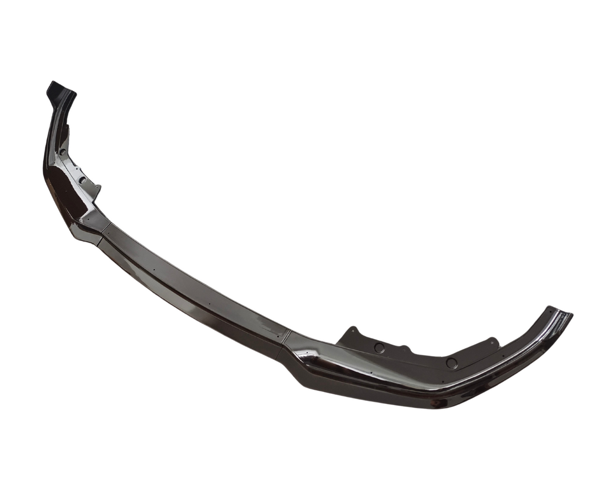 A shiny, curved car bumper sits isolated on a white background. Its sleek, metallic surface has slight curves and indentations typical of a vehicle's front end component.