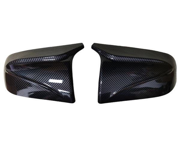 Two glossy carbon fiber car mirror covers, resting side by side against a white background, highlighting their sleek, aerodynamic design and polished finish.