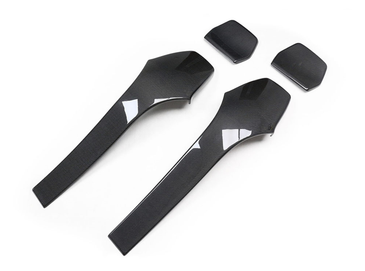 Two sleek, black carbon fiber car trim pieces are positioned on a plain white background. Above them, two smaller matching components are aligned, showcasing an elegant design.