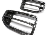 Two carbon fiber car grille inserts, one larger and one smaller, sit against a white background. The rectangular frames feature a glossy finish and prominent horizontal slats.