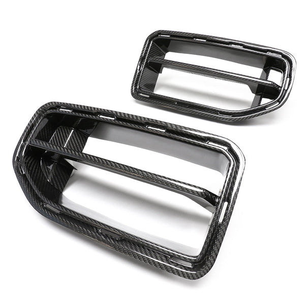 Two carbon fiber car grille inserts, one larger and one smaller, sit against a white background. The rectangular frames feature a glossy finish and prominent horizontal slats.