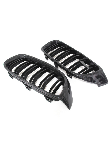Two carbon fiber car grilles with slatted designs lying side by side on a plain white background. The grilles have shiny, textured surfaces and a sleek, aerodynamic shape.