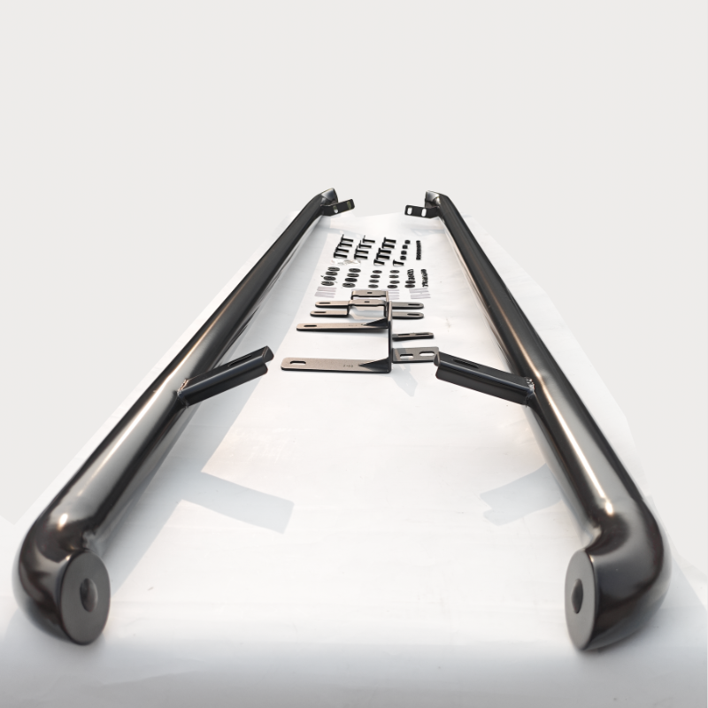 Two black metal bars lie parallel on a white surface, surrounded by various mounting brackets and screws arranged systematically, suggesting an assembly kit.