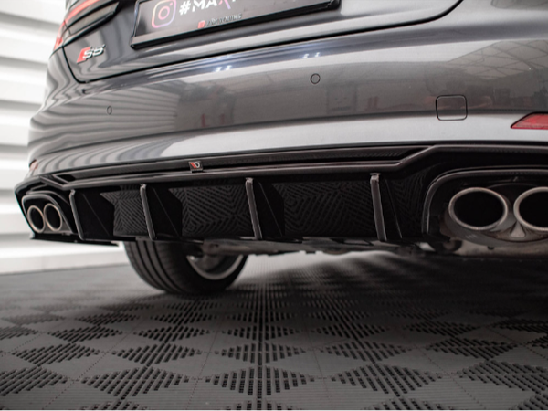 The rear of a gray car features dual exhaust pipes and a sporty diffuser. It’s parked on a patterned surface in a well-lit garage. Text: "S3," "maxhaust," "Instagram logo #MAXhaust," "YouTube logo MaxhaustTV."