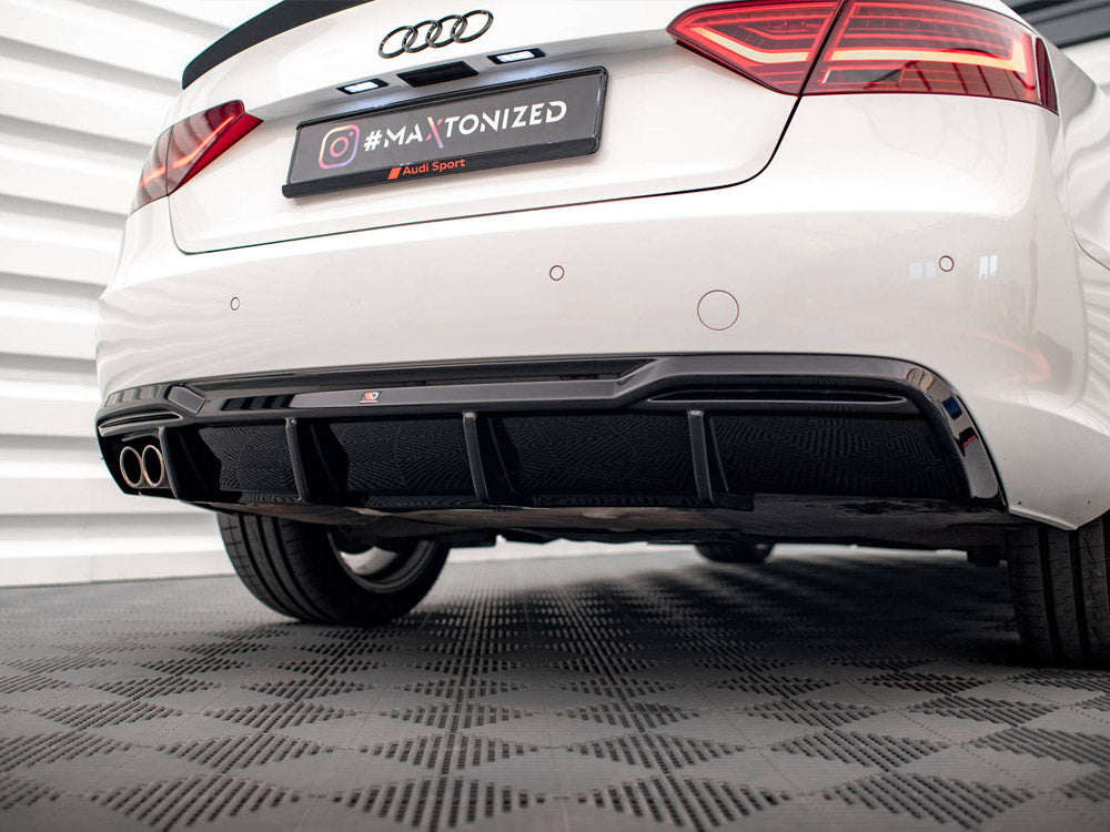 A white car's rear view features dual exhausts and a black diffuser. It is parked on a textured floor. The license plate reads "#MAXTONIZED @Audi Sport" with Audi badge above.
