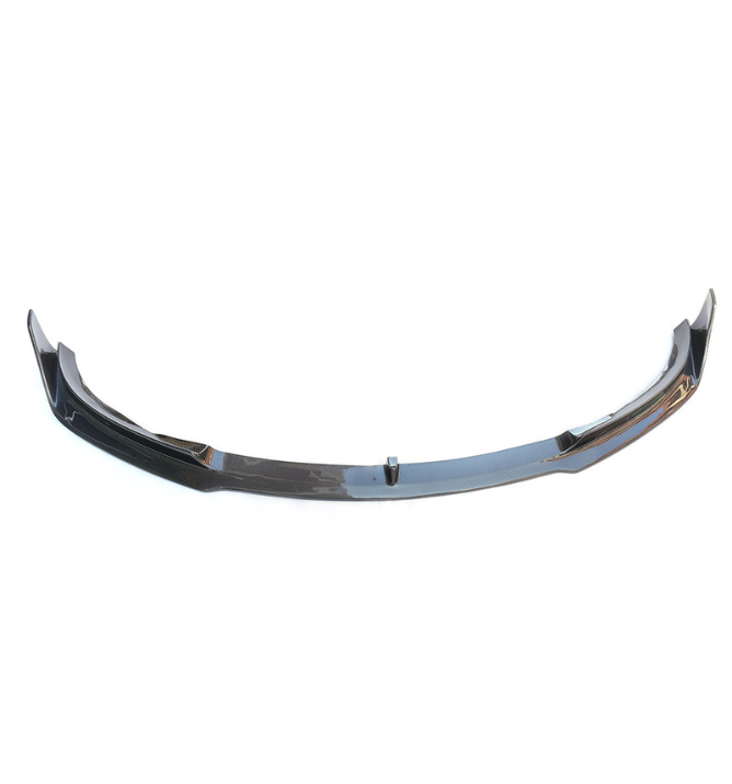 A black carbon fiber car front lip spoiler rests on a plain white background, showcasing its sleek, aerodynamic design with raised ends and slight curvature.